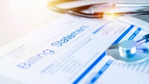 Medical billing statement with a stethoscope and pen on a desk.
